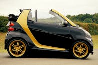 一辆设计时尚、边框闪亮的黑色与金色敞篷车停在户外