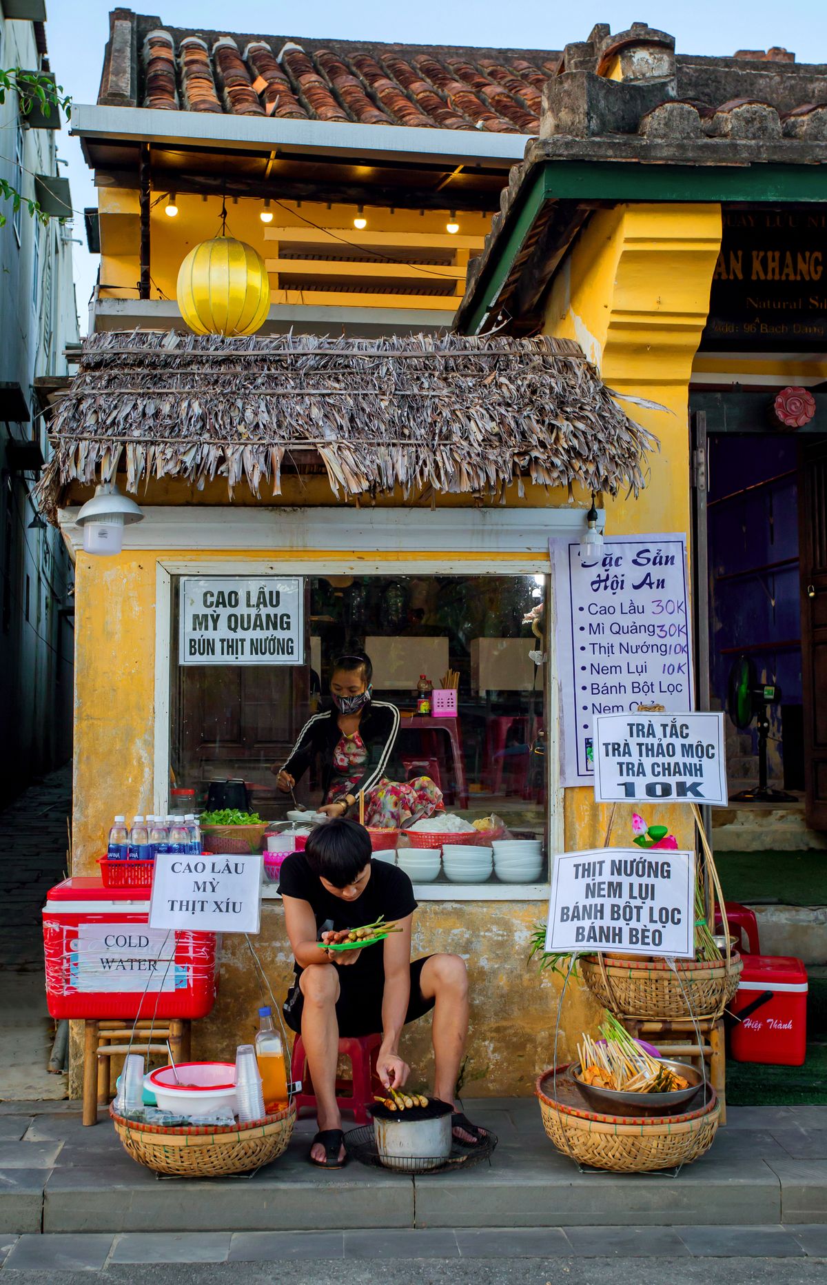 A street-food stall in Hoi An with local dishes listed on its sign