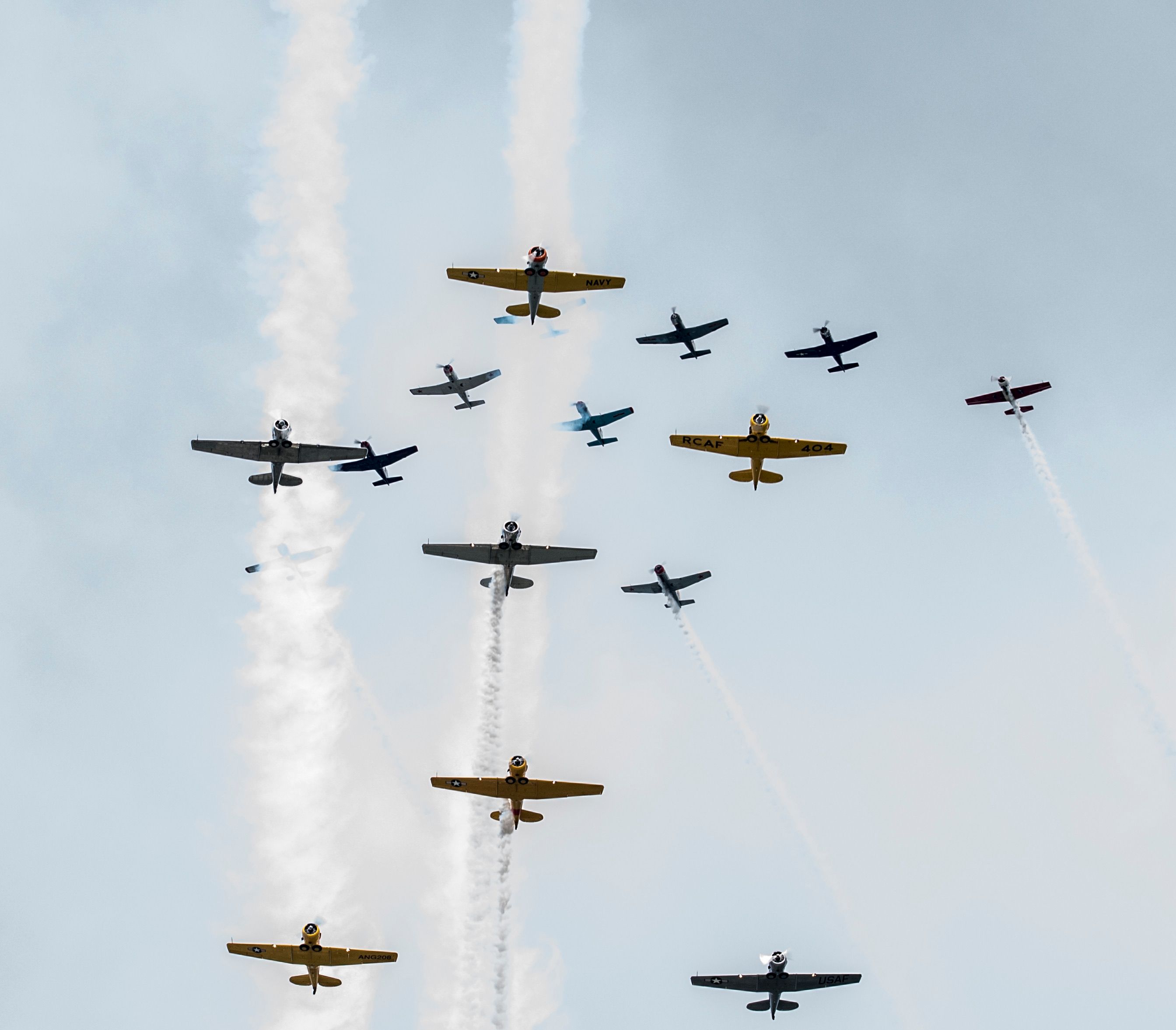 A group of vintage aircraft performing aerobatic formations in a clear sky.
