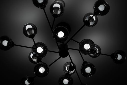 Free A sleek black chandelier with spherical bulbs viewed from below in a dramatic lighting setup. Stock Photo