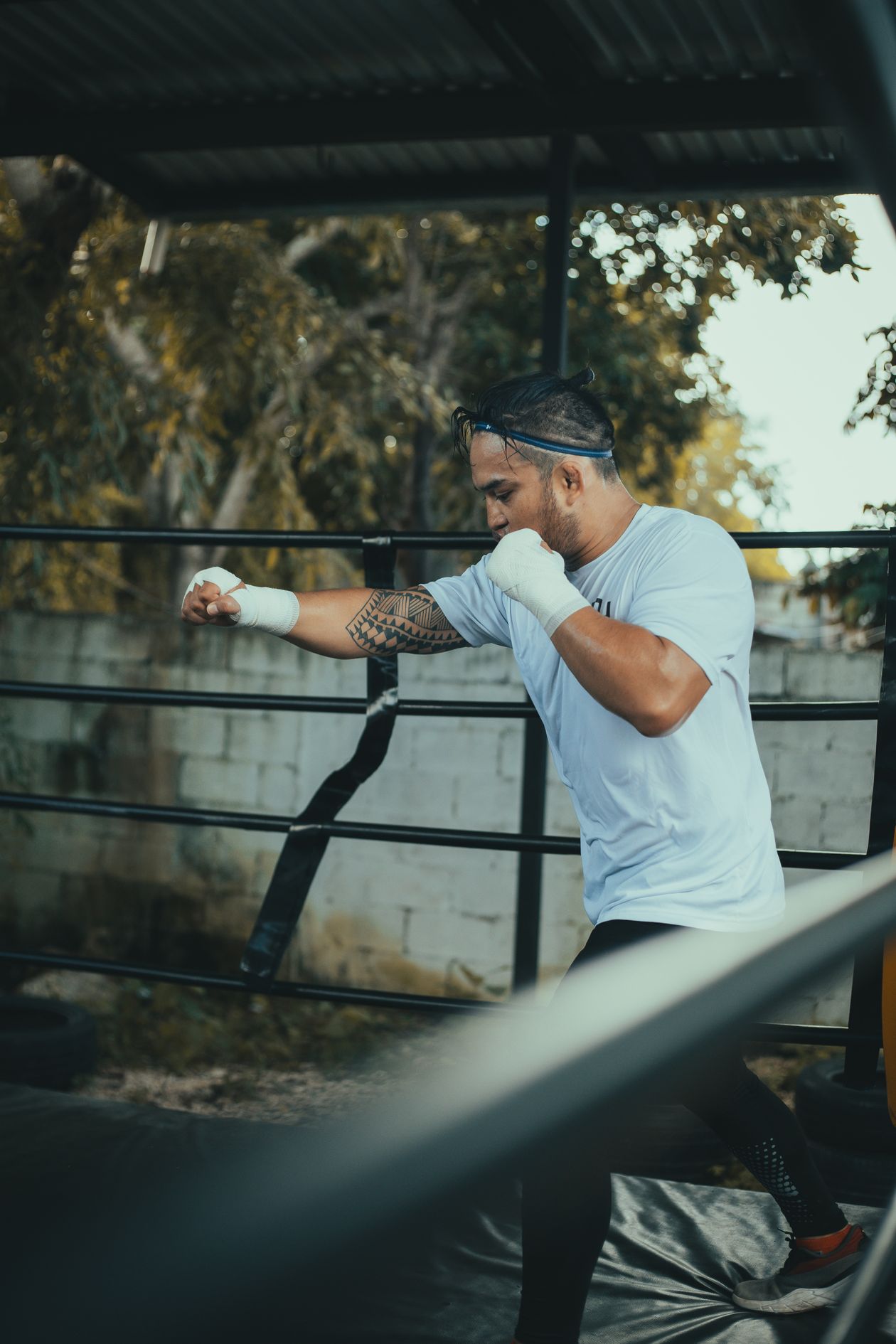 Boxeador entrenando golpes rectos en un cuadrilátero al aire libre.