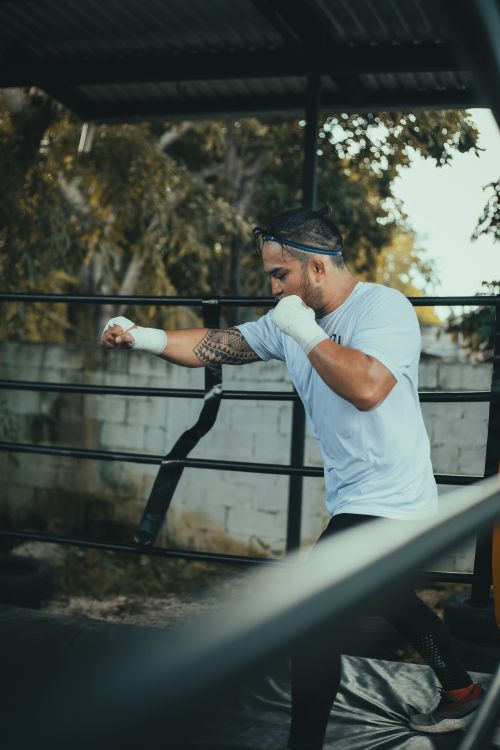 Free A determined boxer practices punches in an outdoor ring, focusing on technique. Stock Photo