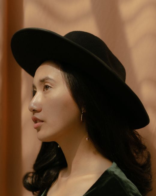 Side profile of a stylish woman wearing a fedora, captured in warm light.