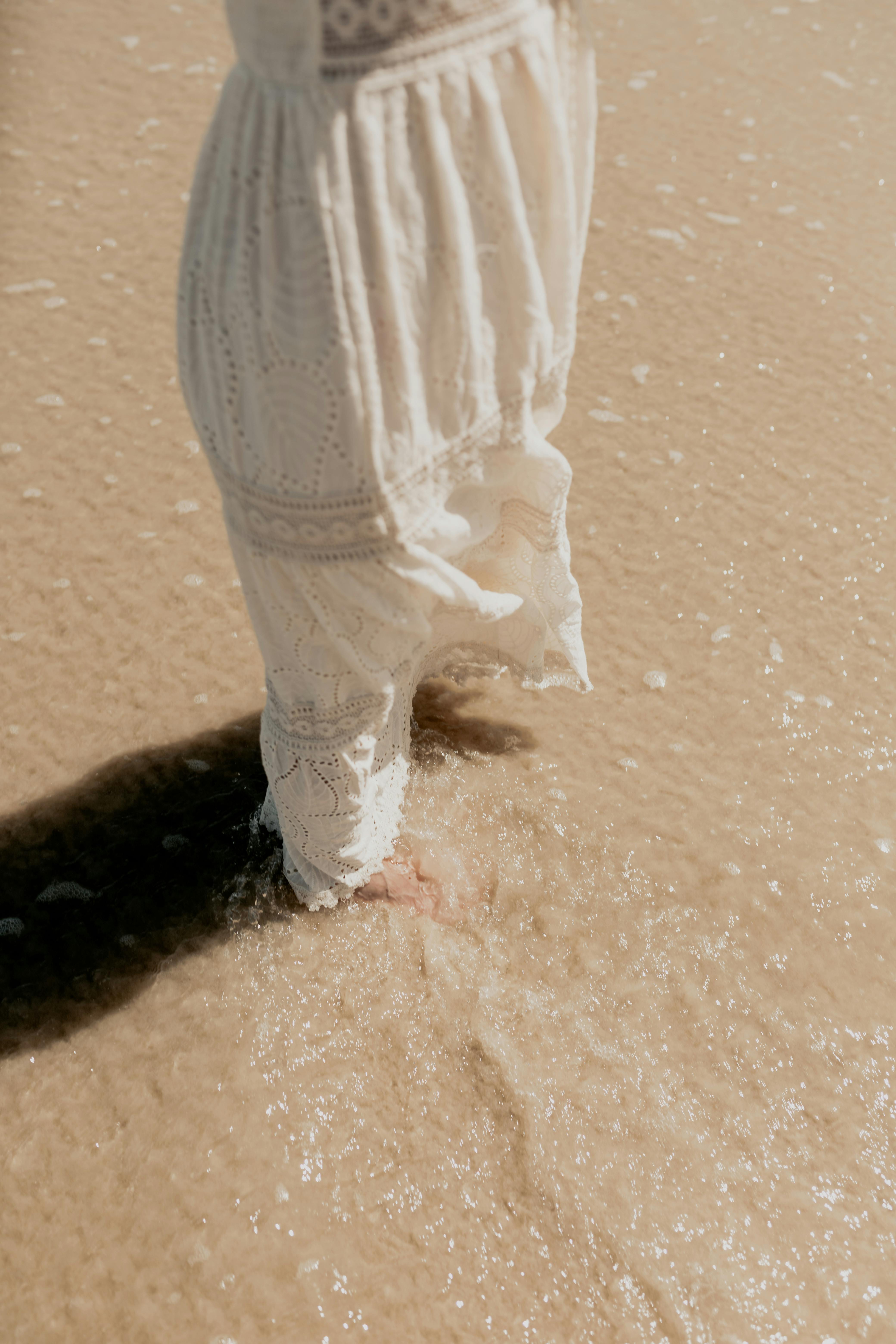 child enjoying beach waves in white dress