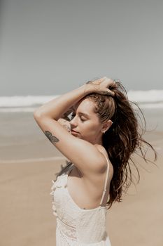 Young woman enjoying a sunny day at the beach, feeling the breeze.