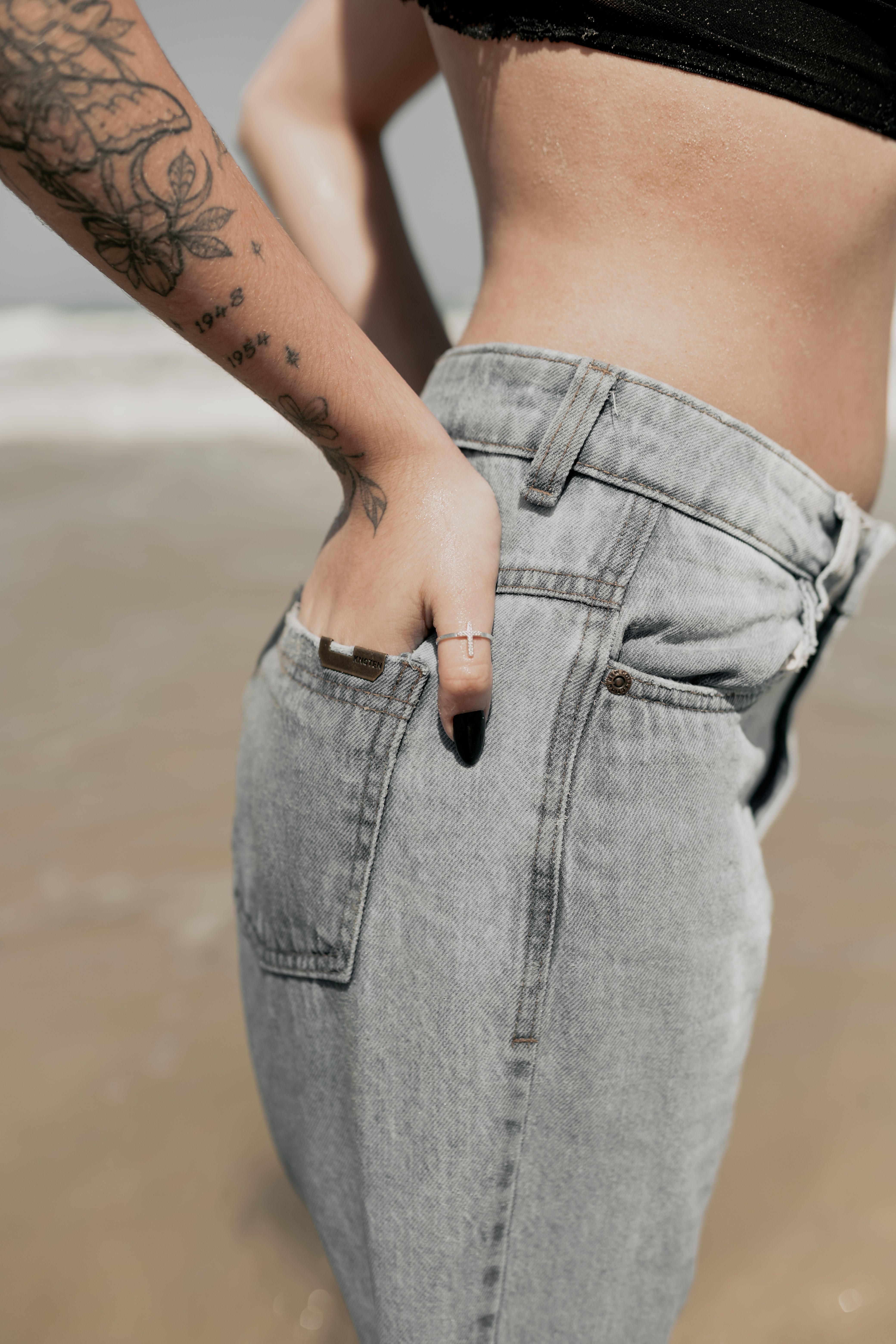 Stylish woman with tattoo in denim shorts enjoying a sunny beach day.