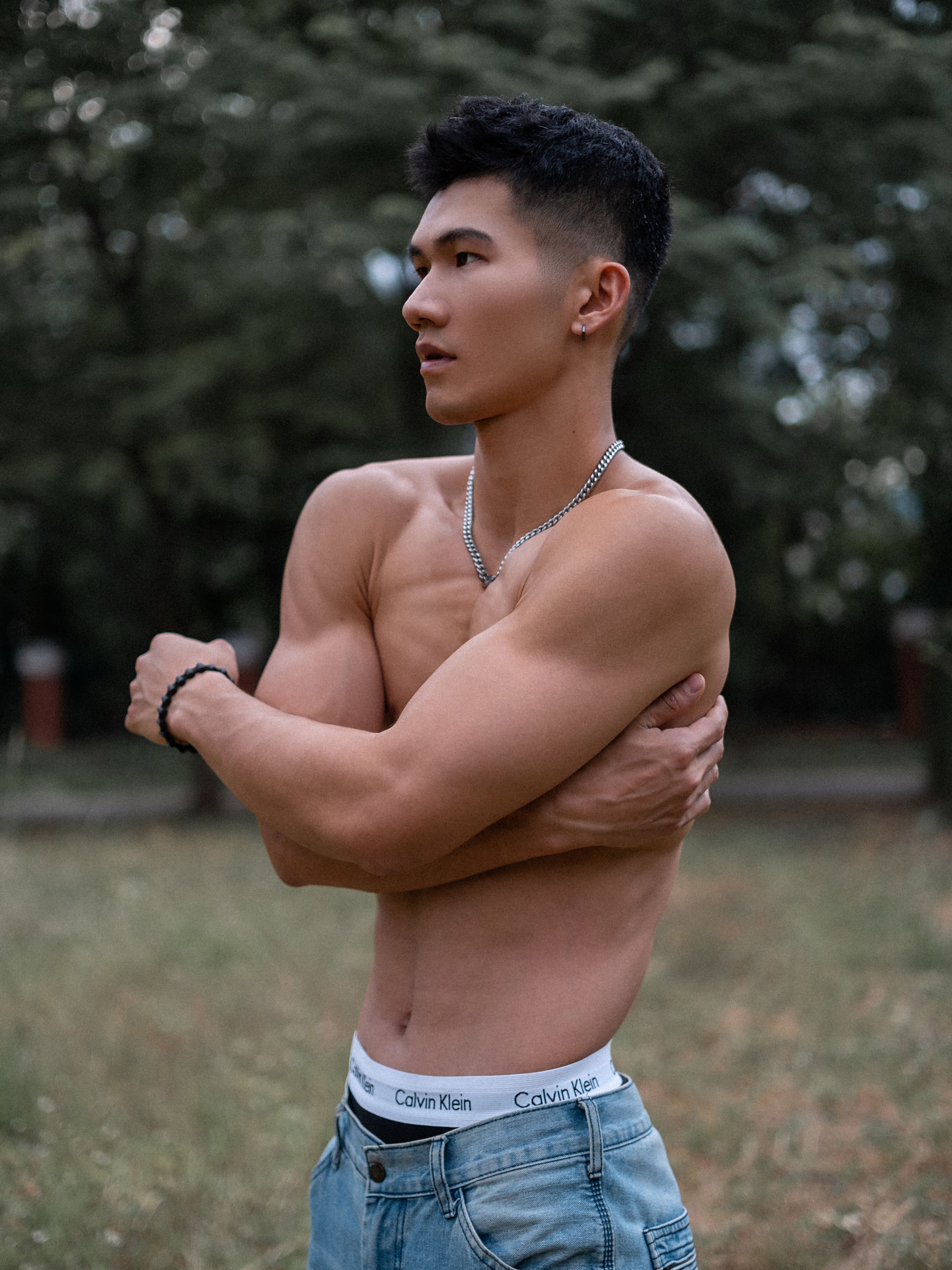 Portrait of a young shirtless athletic man outdoors, showcasing fitness and style.