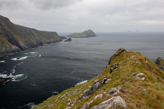 Breathtaking view of rocky cliffs and coastline in County Kerry, Ireland, under cloudy skies.