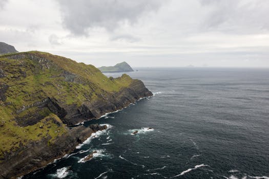 Dramatic aerial view of rugged cliffs meeting the ocean on a cloudy day.