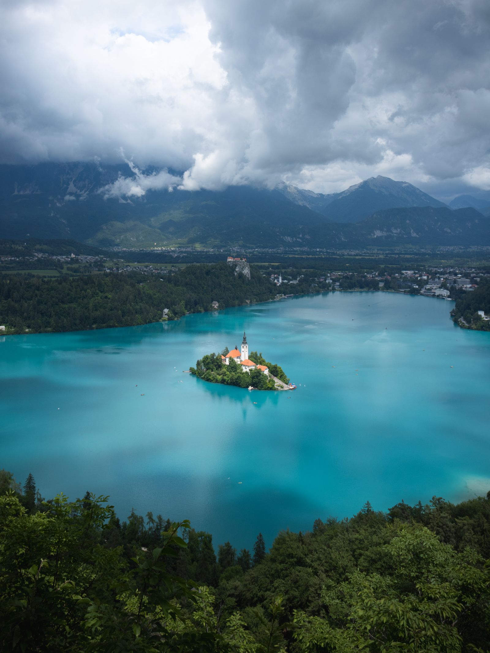 An alpine lake with a church on a small island, mountains behind