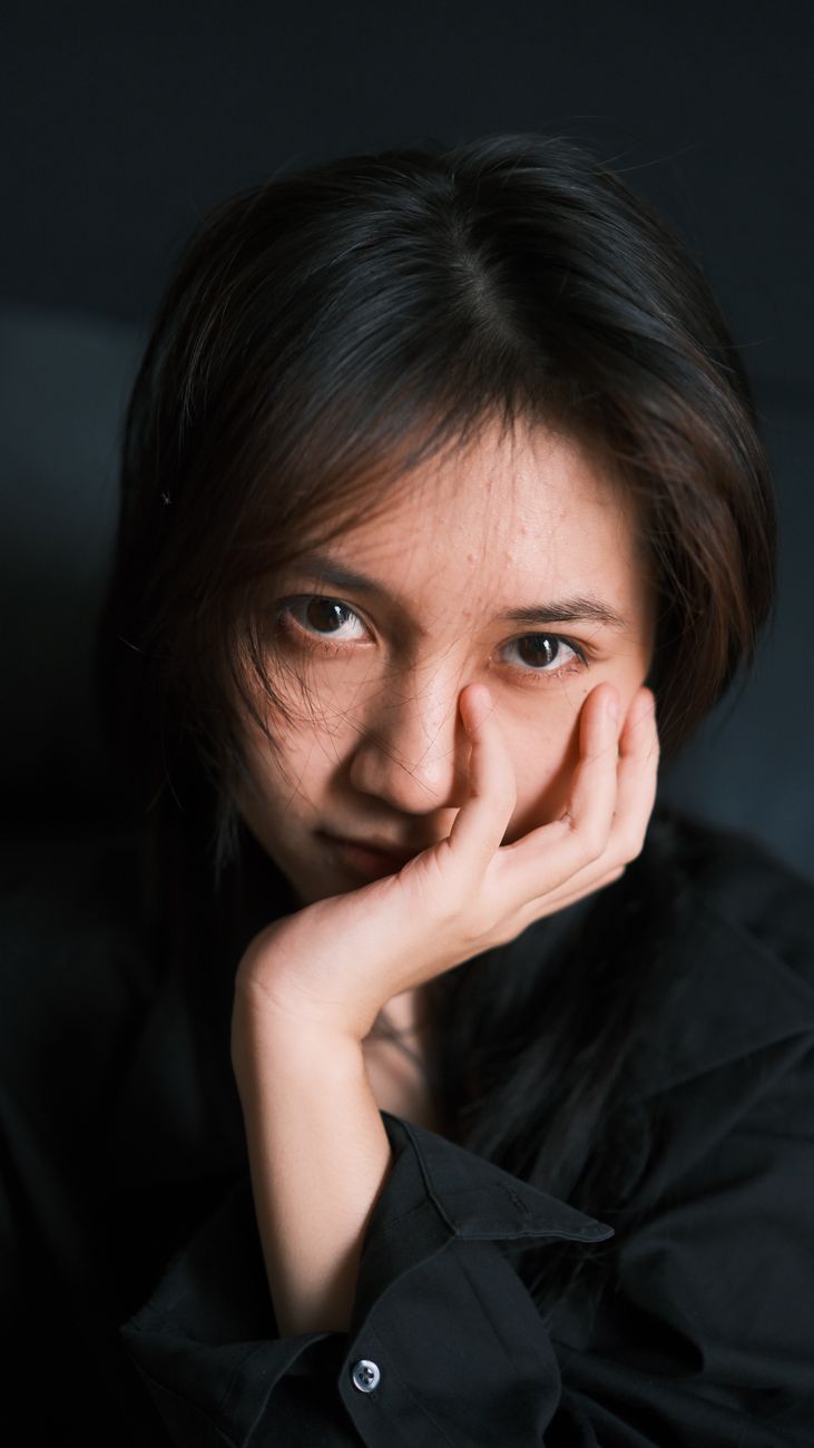 Close-up portrait of a young woman gazing thoughtfully. Intimate and moody vibe.