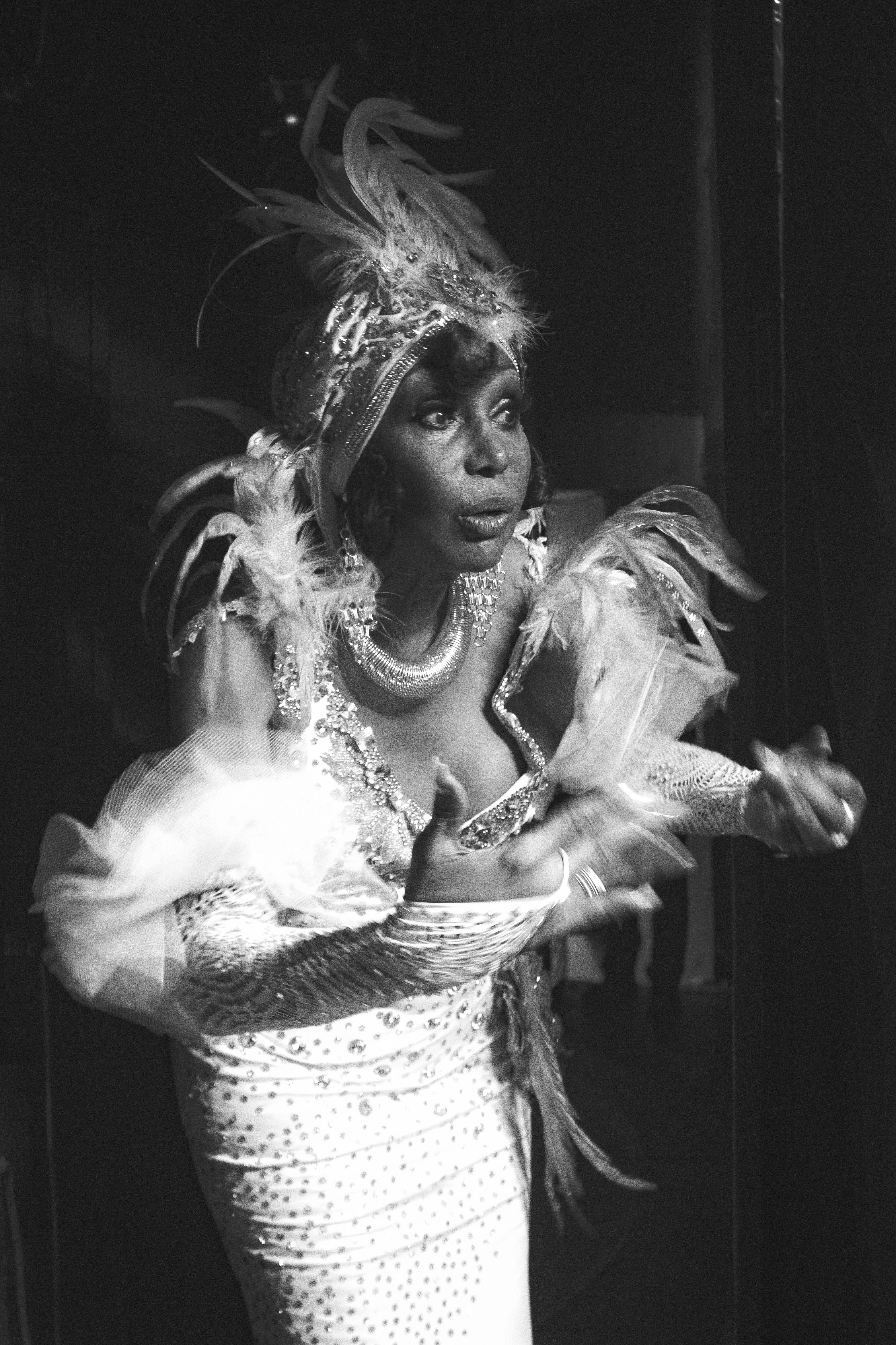Free Black and white image of a performer in an elaborate feathered costume preparing backstage. Stock Photo