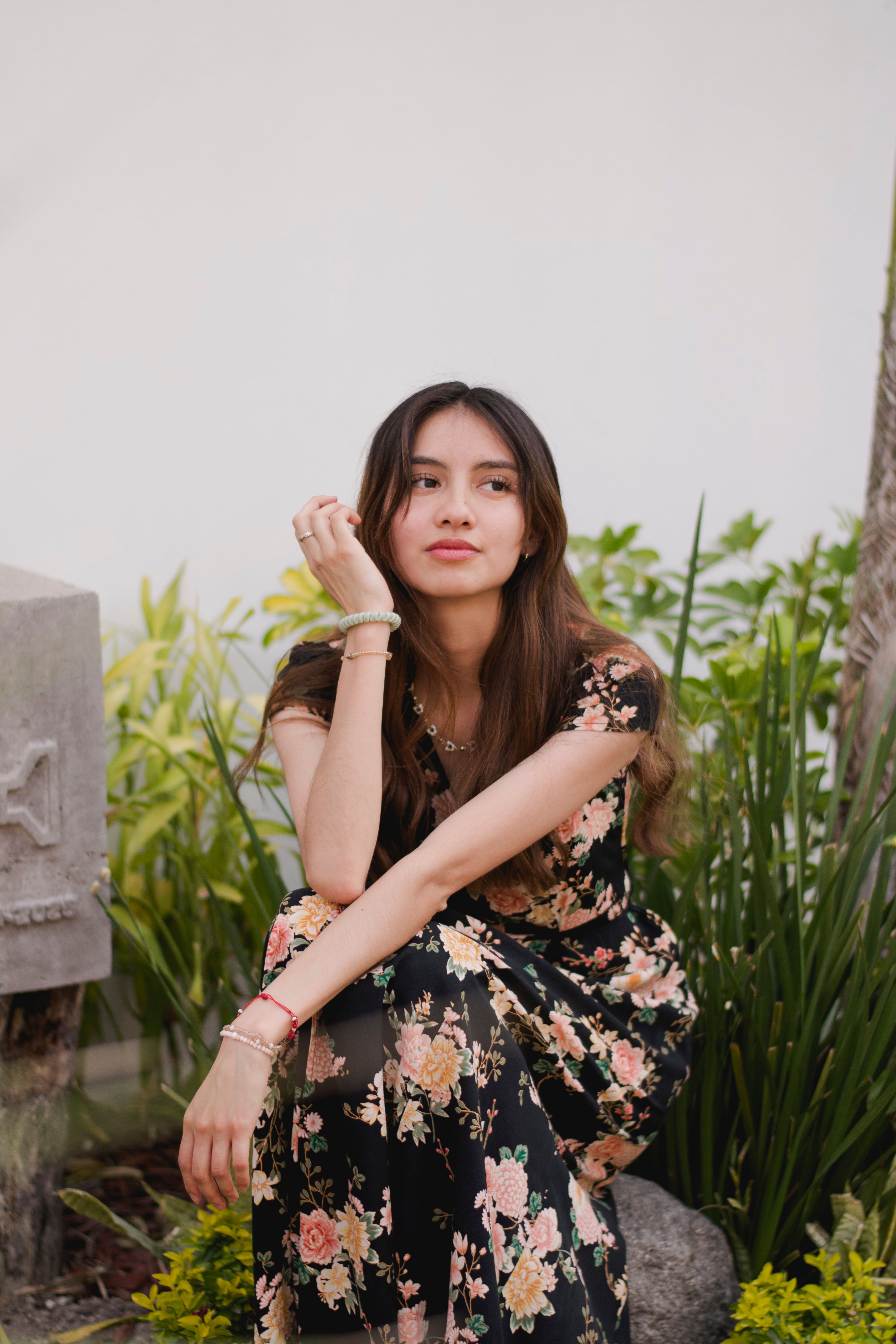 Elegant Woman in Floral Dress Sitting Outdoors · Free Stock Photo