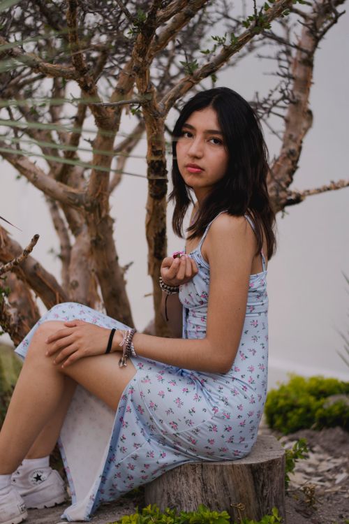 Free Young woman in a floral dress sitting outdoors, captured thoughtfully. Stock Photo