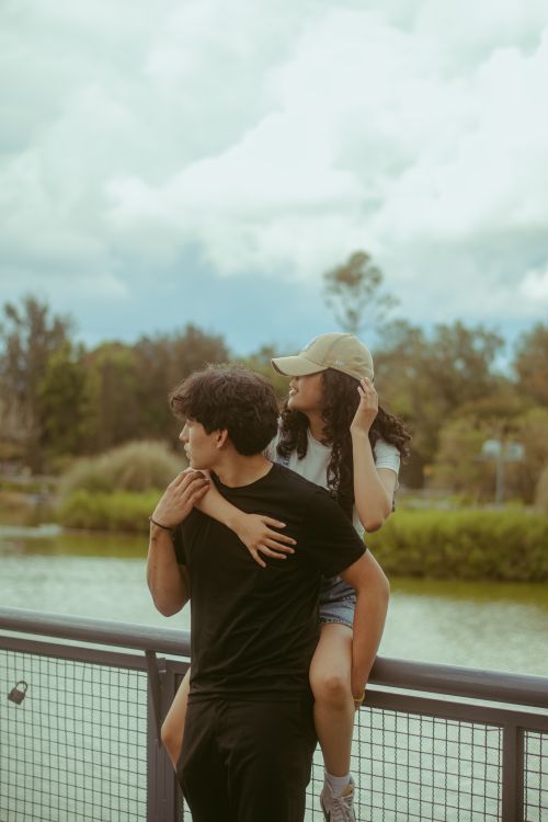 Free A young couple spends quality time together by a serene riverside, embracing and sharing a moment outdoors. Stock Photo