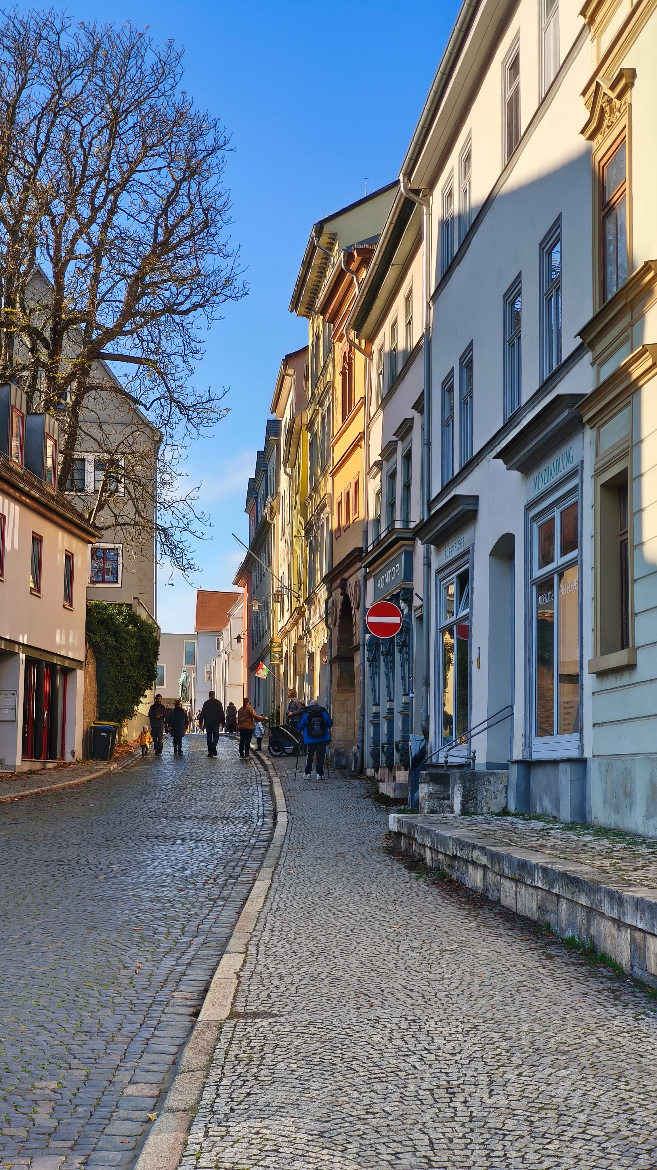 Historic Weimar street with people walking, showcasing classic European architecture.