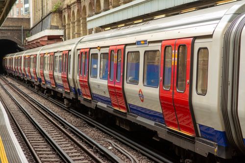 Free A vibrant red and blue subway train at an outdoor urban station on a cloudy day. Stock Photo
