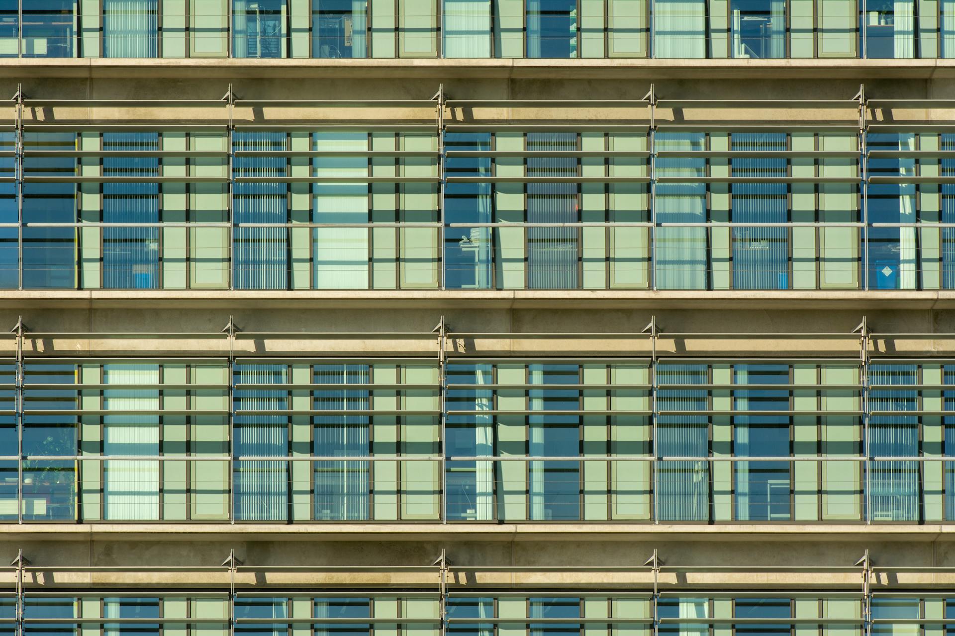 Close-up of a modern building facade with repetitive grid pattern and glass windows.