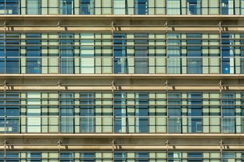 Free Close-up of a modern building facade with repetitive grid pattern and glass windows. Stock Photo