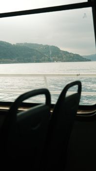 A serene lake view captured through a moving train window with empty seats.