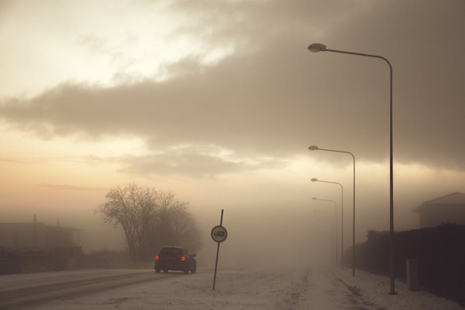 Moody evening scene with fog enveloping a road and a car in Estonia.
