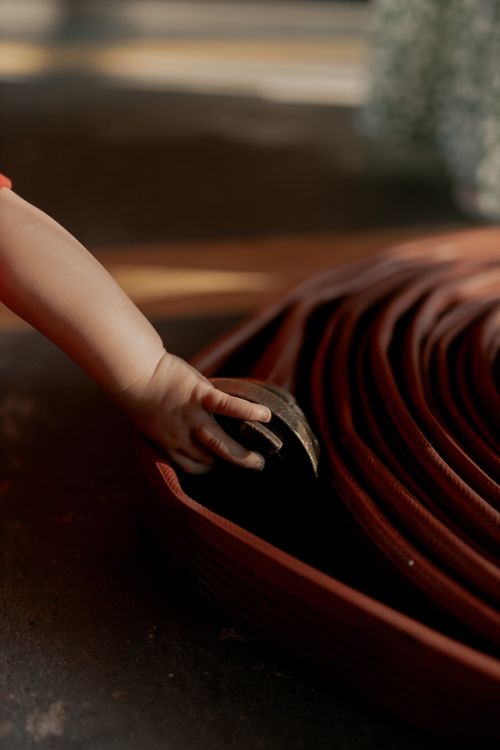 Free Close-up of a child's hand gripping a coiled garden hose on a sunny day. Stock Photo