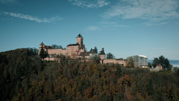 Aerial shot of Haut-Koenigsbourg Castle amidst a vibrant autumn forest in Kintzheim, France.