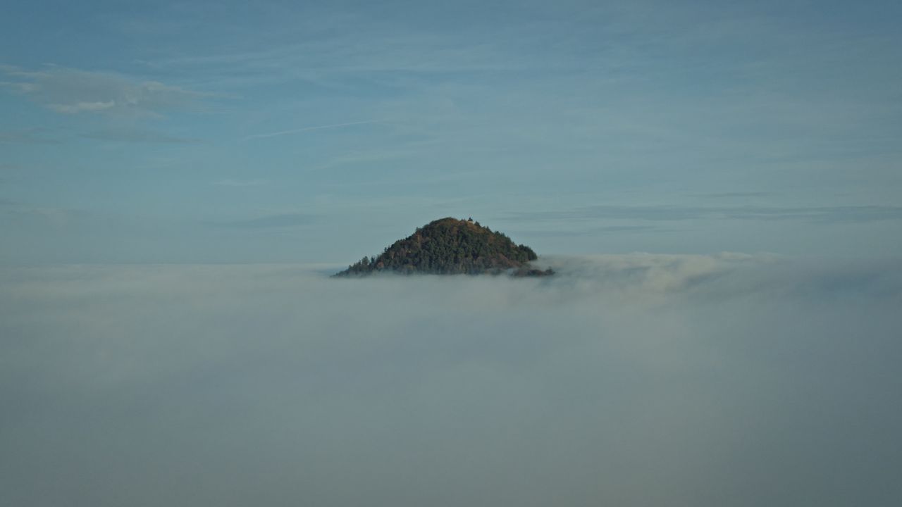 a hilltop emerges from thick fog in kintzheim france creating a mystic