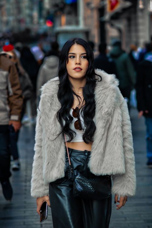 Free Woman in a gray fur coat walking confidently down a busy city street. Stock Photo