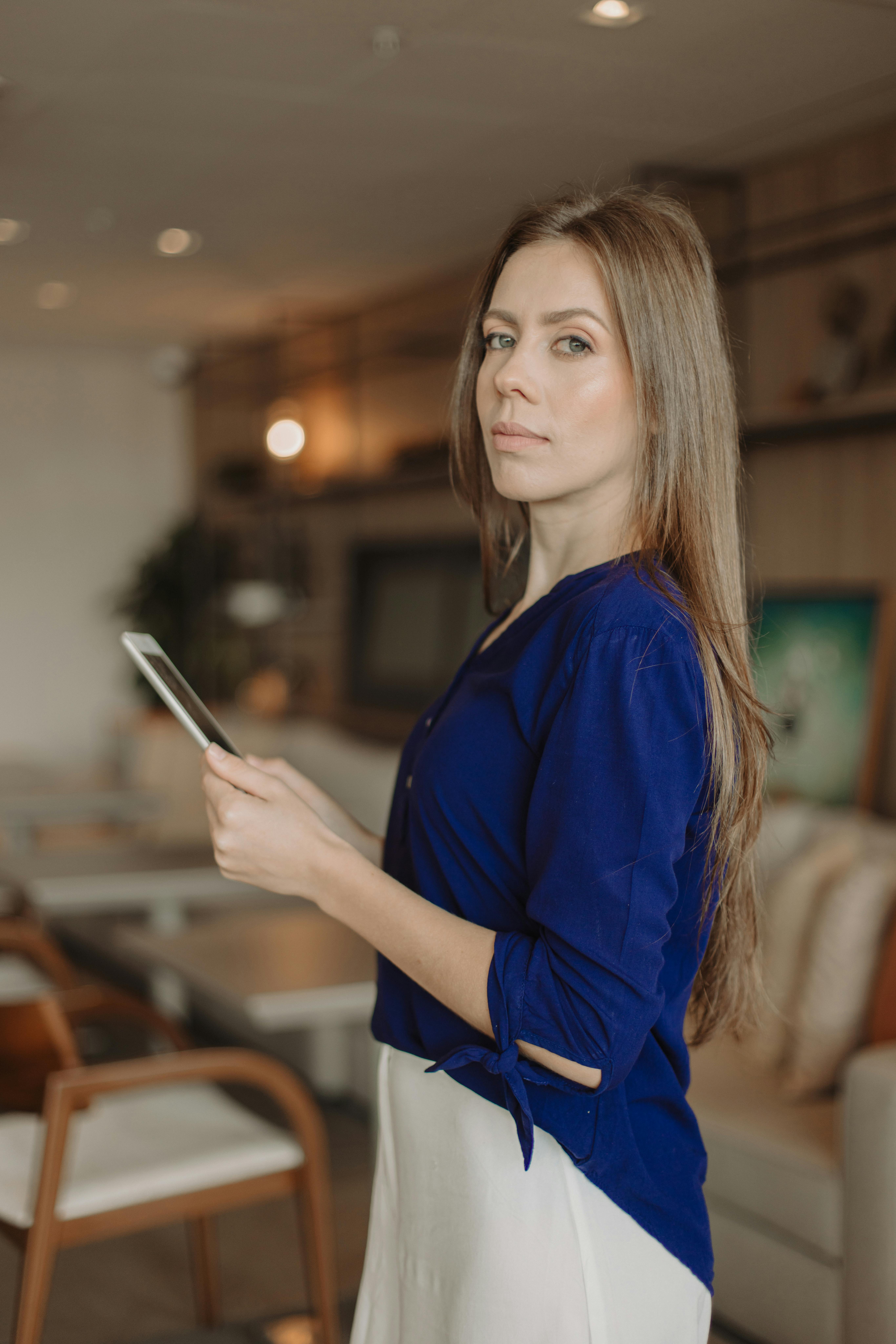 ฟรี ผู้หญิงกำลังถือแท็บเล็ตในห้องในร่มที่มีสไตล์ สะท้อนถึงไลฟ์สไตล์สมัยใหม่ คลังภาพถ่าย