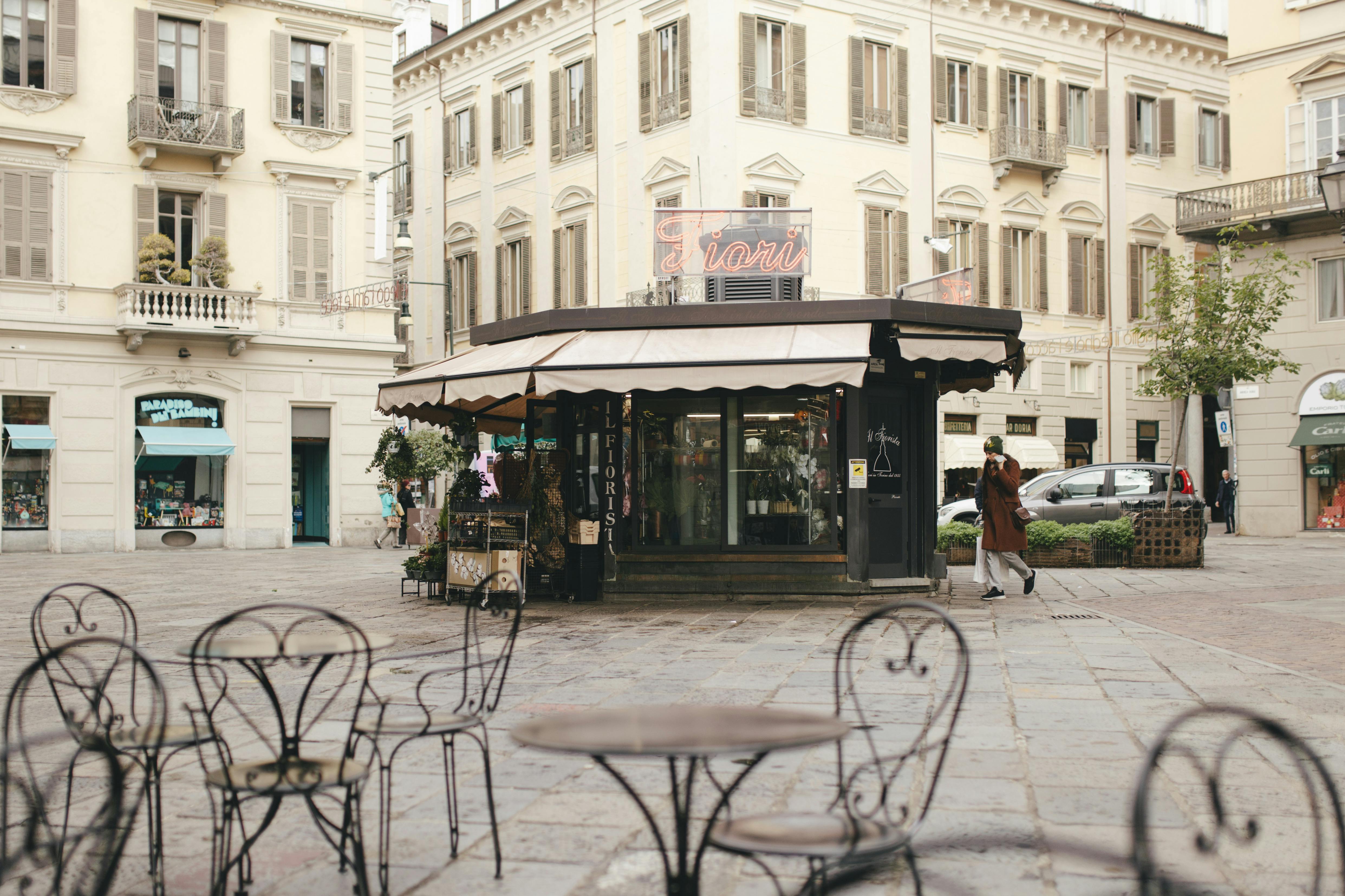 Beautiful Italian square with outdoor cafes, florist shop, and classic architecture, capturing a peaceful urban scene.