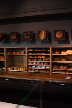 A wooden shelf filled with a variety of freshly baked breads in a bakery setting.