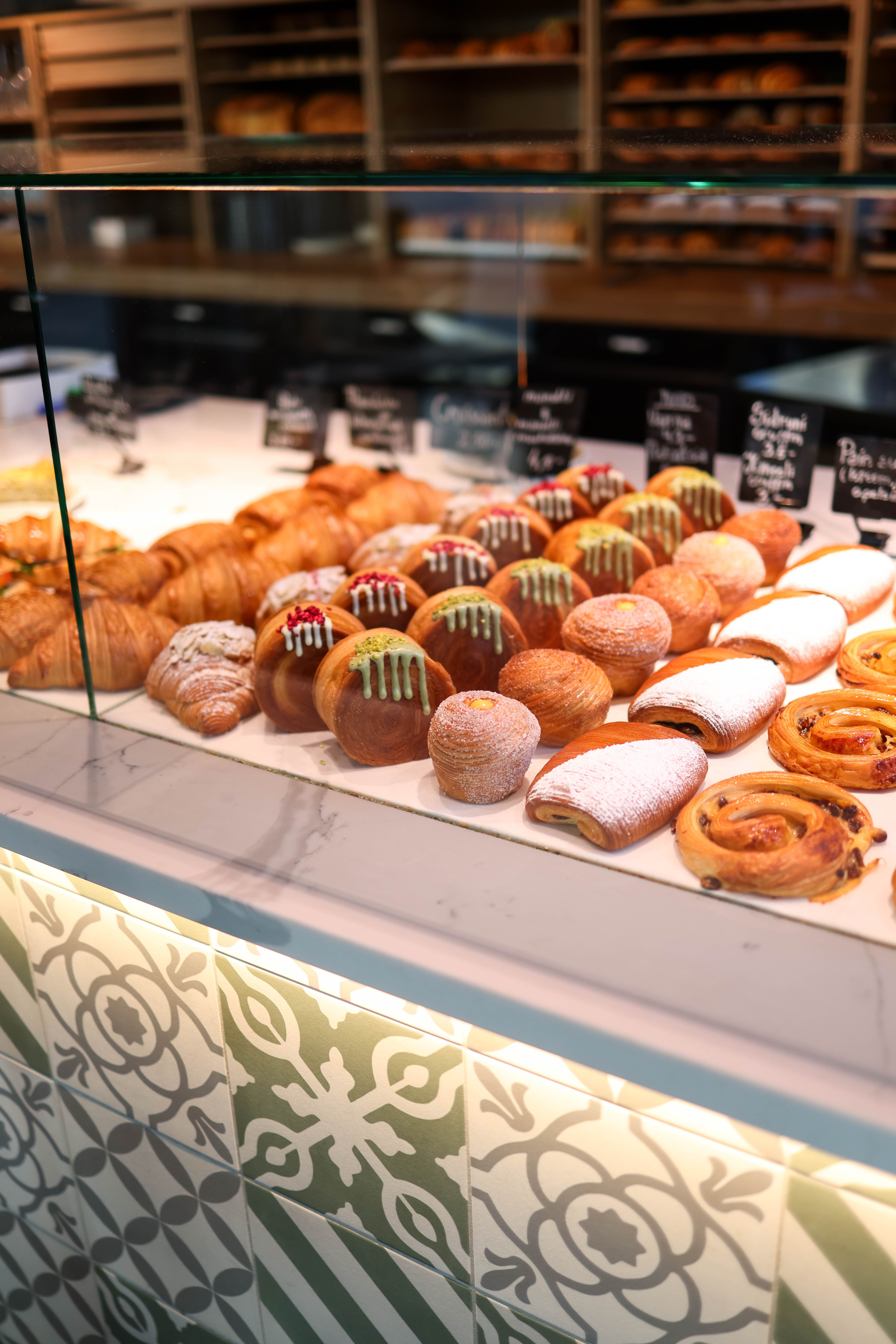 A variety of pastries displayed in a bakery counter, showcasing croissants and danishes.