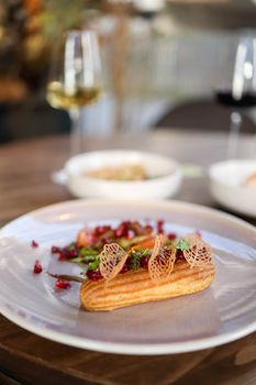 Elegantly plated gourmet eclair with garnish, perfect for fine dining atmosphere.