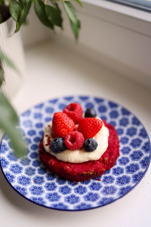 Free Berry tart with cream on a blue patterned plate, topped with strawberries, raspberries, and blueberries. Stock Photo