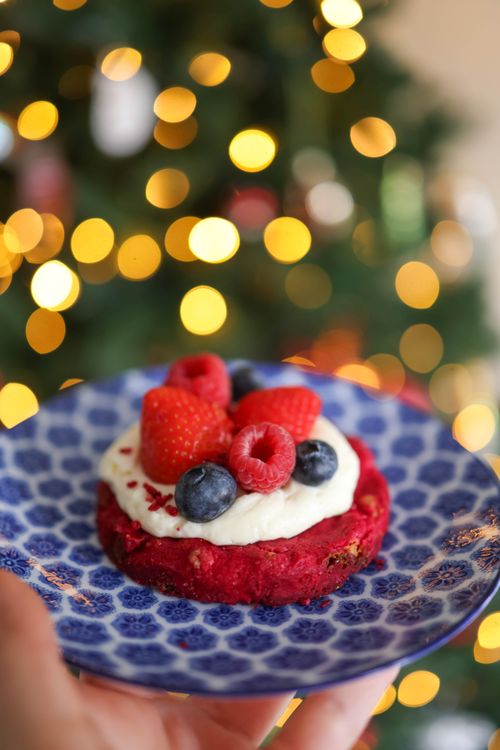 Free Delicious berry-topped dessert on a vibrant blue patterned plate with holiday bokeh lights. Stock Photo
