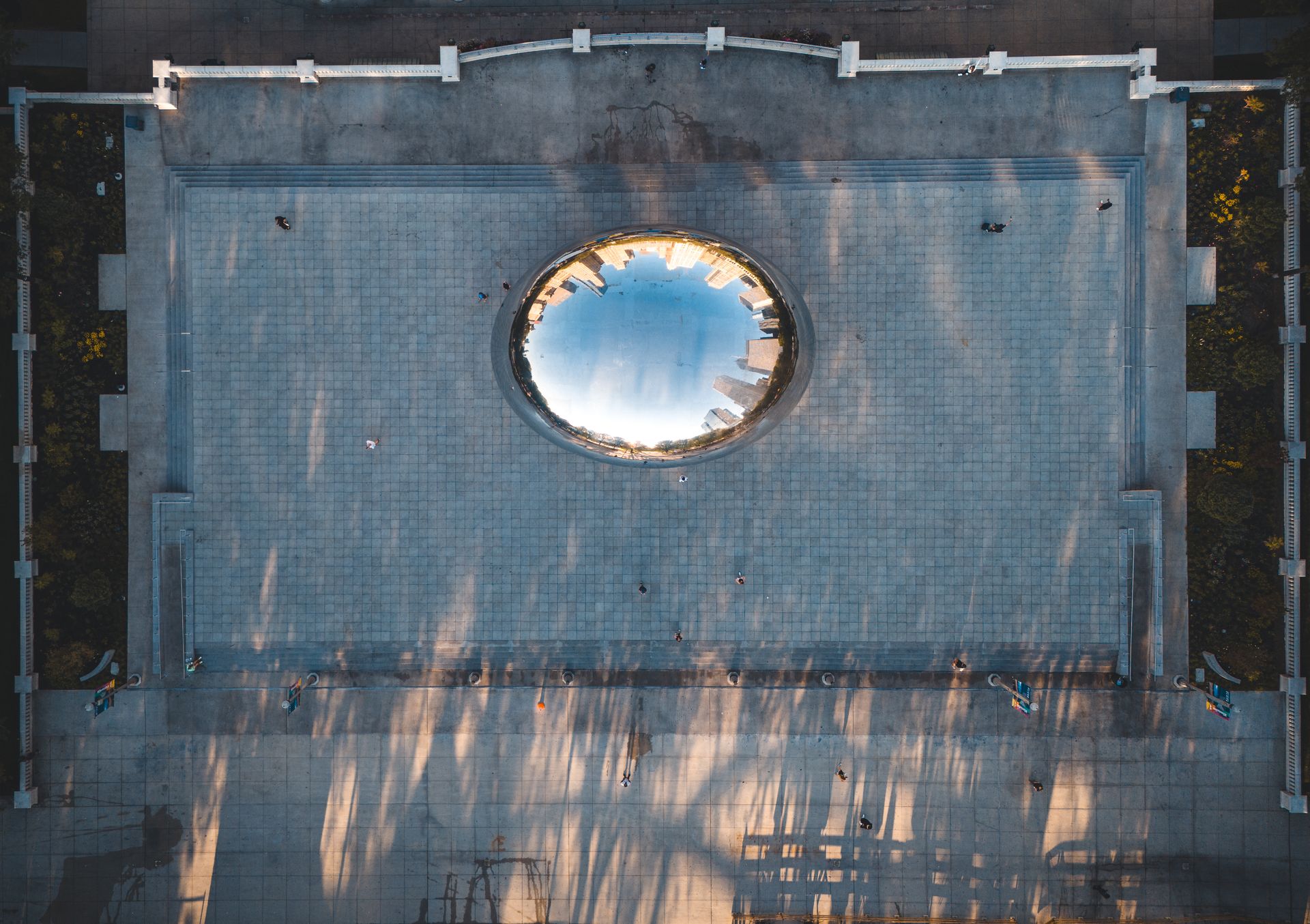 Stunning aerial view of Cloud Gate in Chicago's Millennium Park reflecting the city skyline.