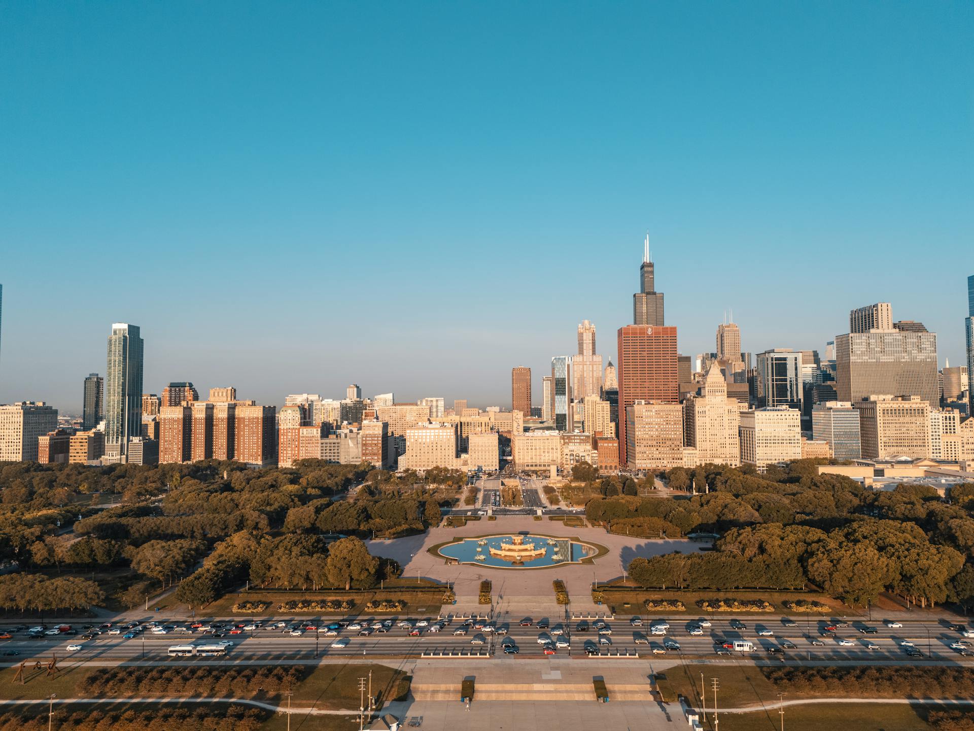 Aerial view of Chicago skyline with Willis Tower and urban park on a sunny day.