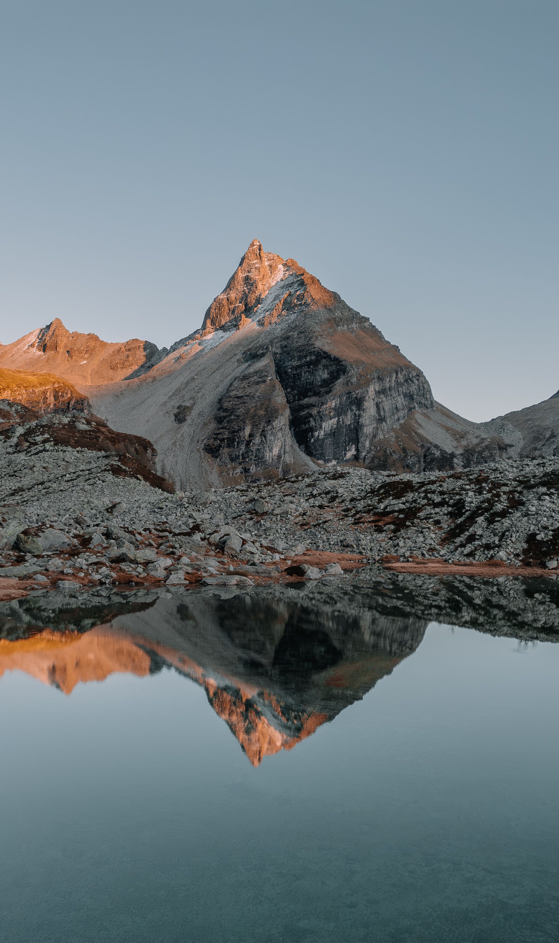 A majestic mountain peak beautifully reflecting in a serene lake at dawn.