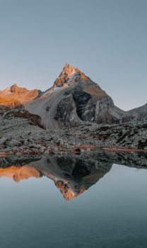A majestic mountain peak beautifully reflecting in a serene lake at dawn.