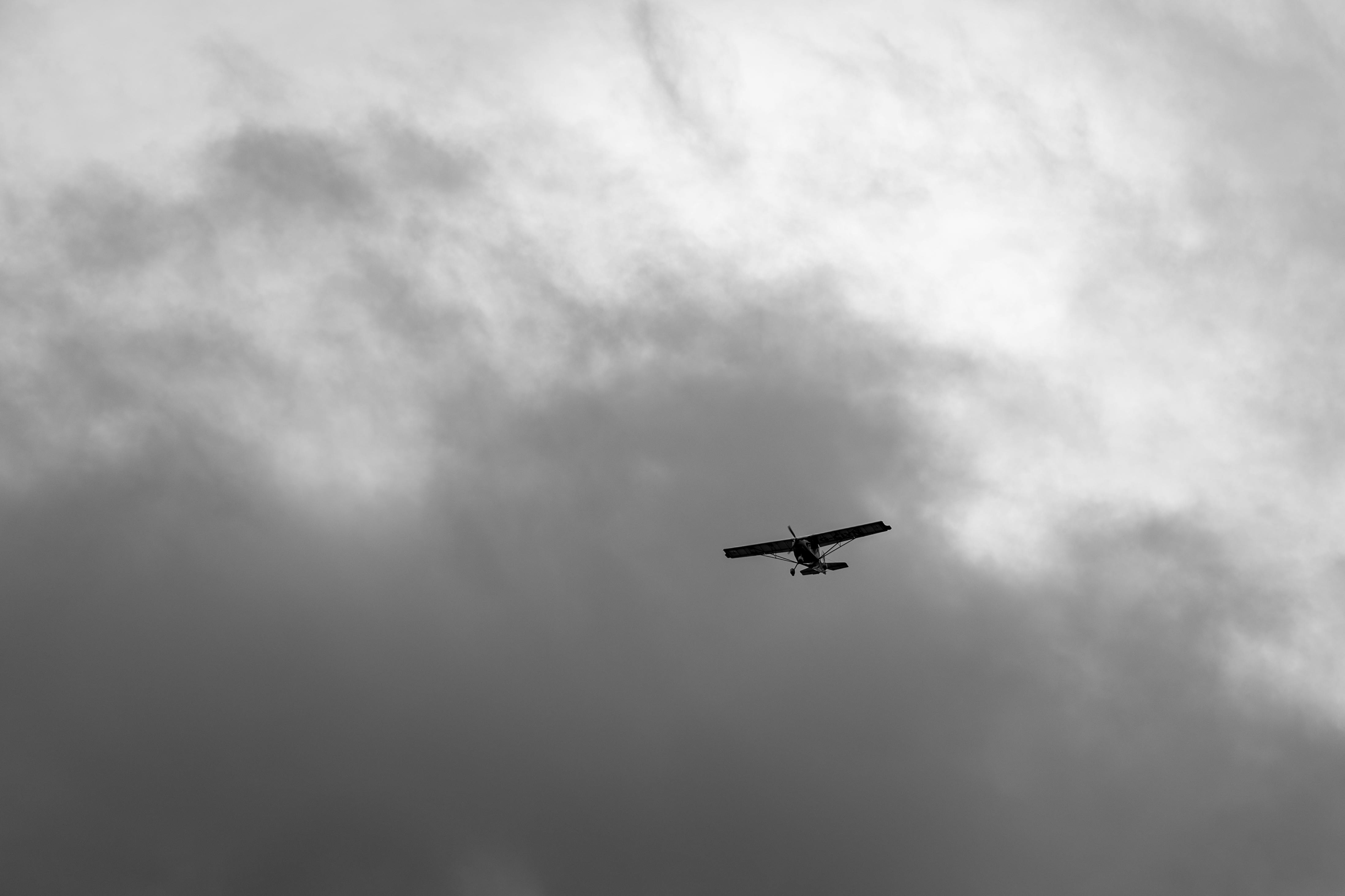 Small aircraft flying through moody overcast sky with dramatic cloud formations — the weather conditions ground school prepares you to interpret