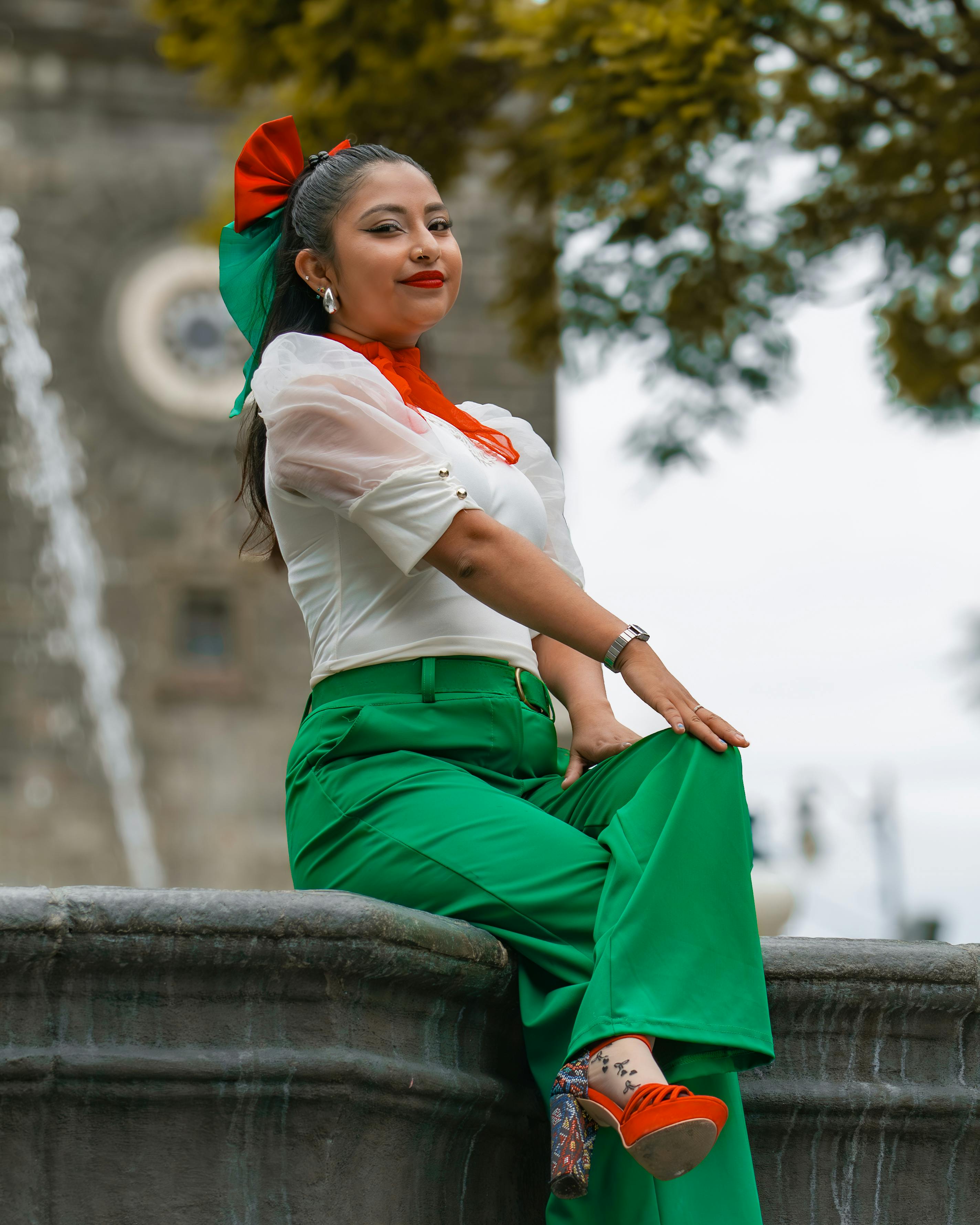 Elegant woman in traditional Mexican attire posing by a historic fountain in Puebla, México.