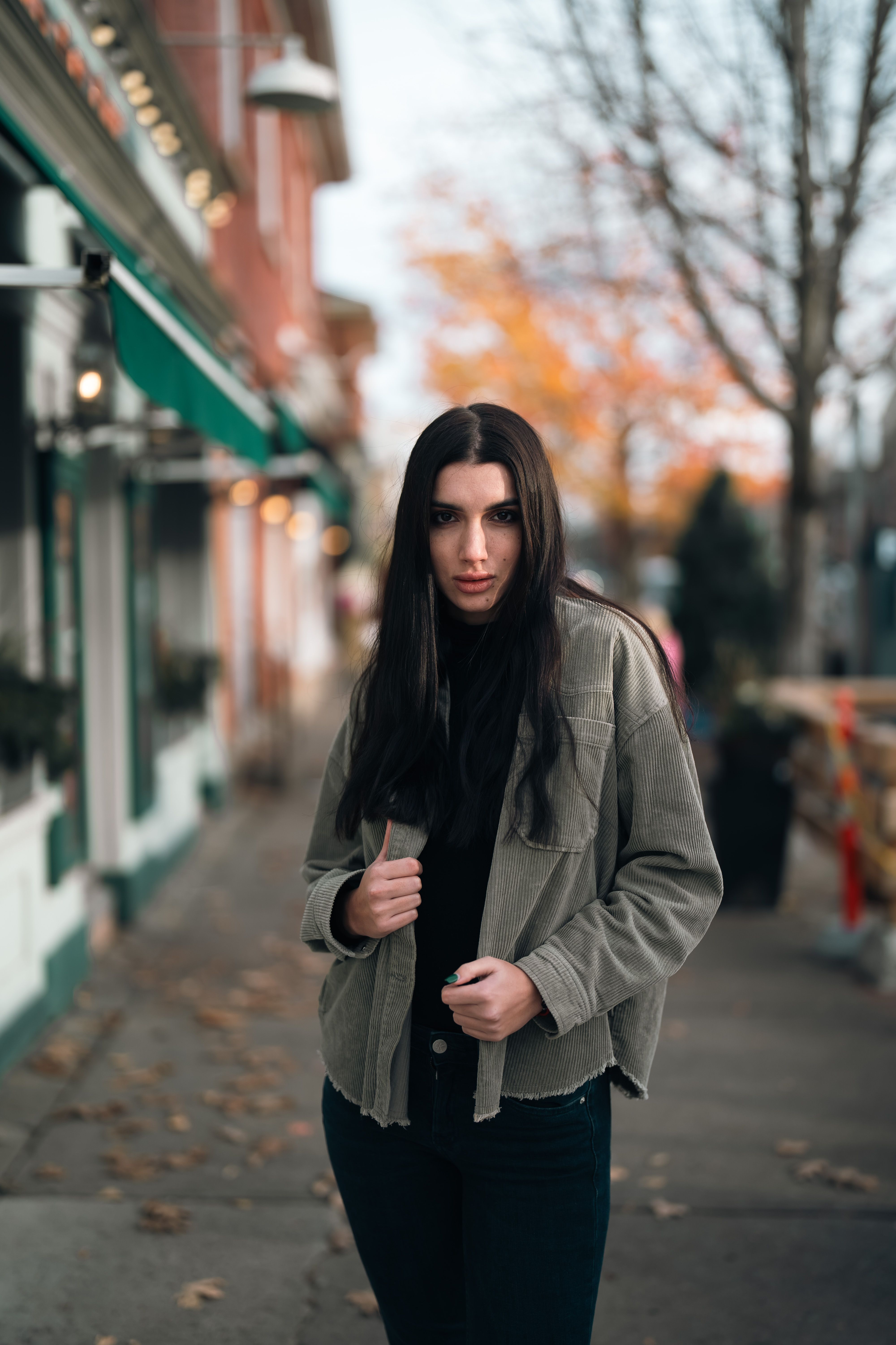 Olive green corduroy barn jacket worn open over a black top and dark jeans on a fall street