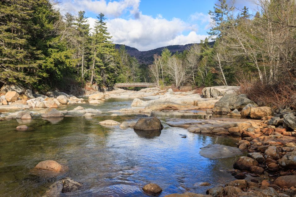 Tranquil river scene with rocks and forest in Albany, New Hampshire, USA.