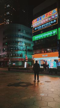 Bustling night scene in Busan, South Korea with neon signs and city lights.