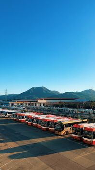 Buses parked at Busan station with scenic mountain backdrop under clear blue sky.