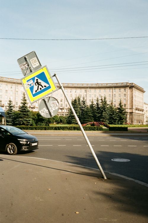 Free Urban street corner with leaning traffic and road signs near a building. Stock Photo