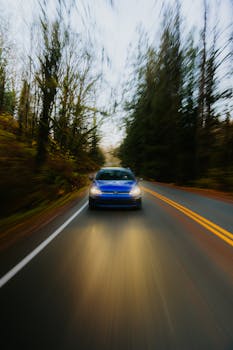 Dynamic shot of a blue car speeding through a forest road.