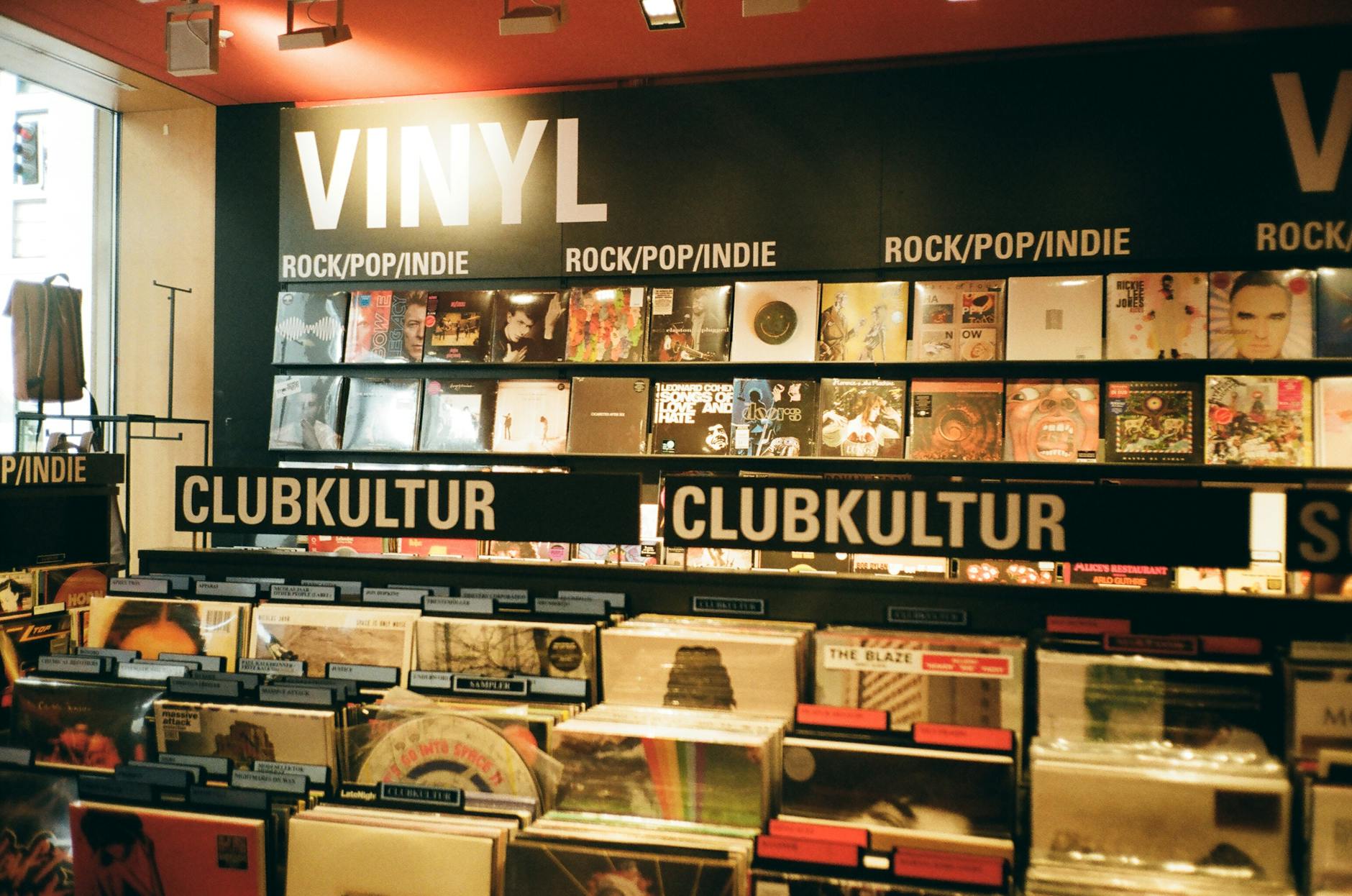 A vibrant indie music store displaying a variety of vinyl records under the categories rock, pop, and club culture.