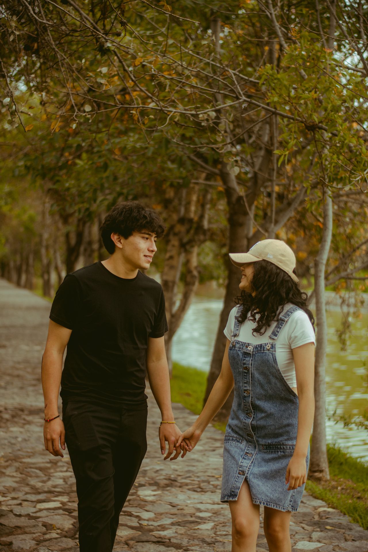 A young couple holding hands walking by a lake